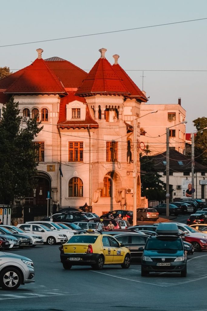 Historic building in Iași, Romania, bathed in sunset with cars and vibrant street life.